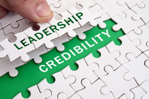The human hand fills the last missing elements of the surface from the jigsaw puzzle. Image with words leadership and credibility